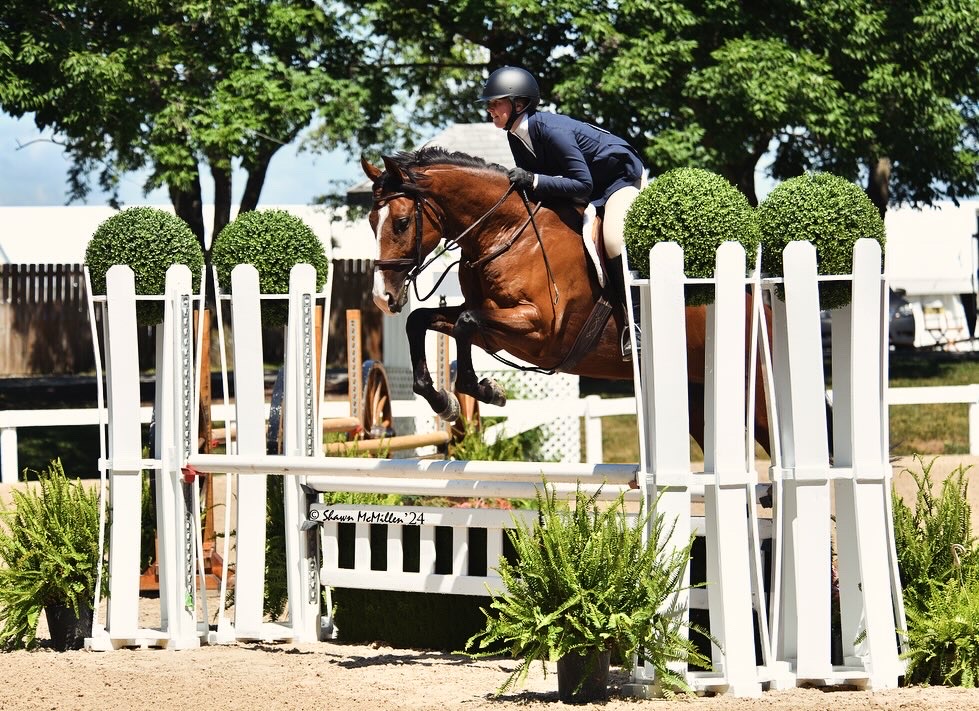 Isabella McCadden jumping a spirited horse named Joey amid lush southern greenery