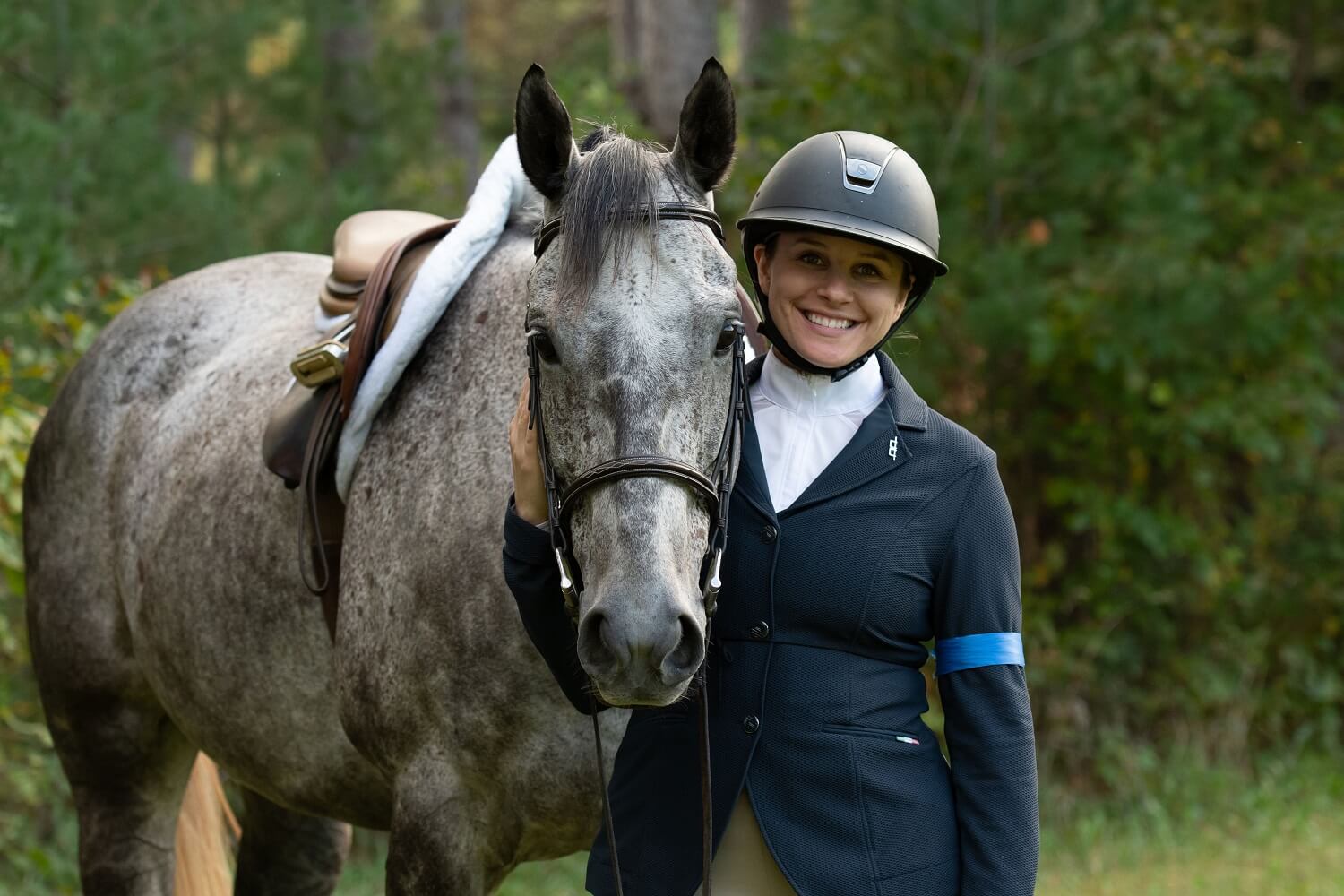 Maria smiling broadly next to a Thoroughbred horse named George